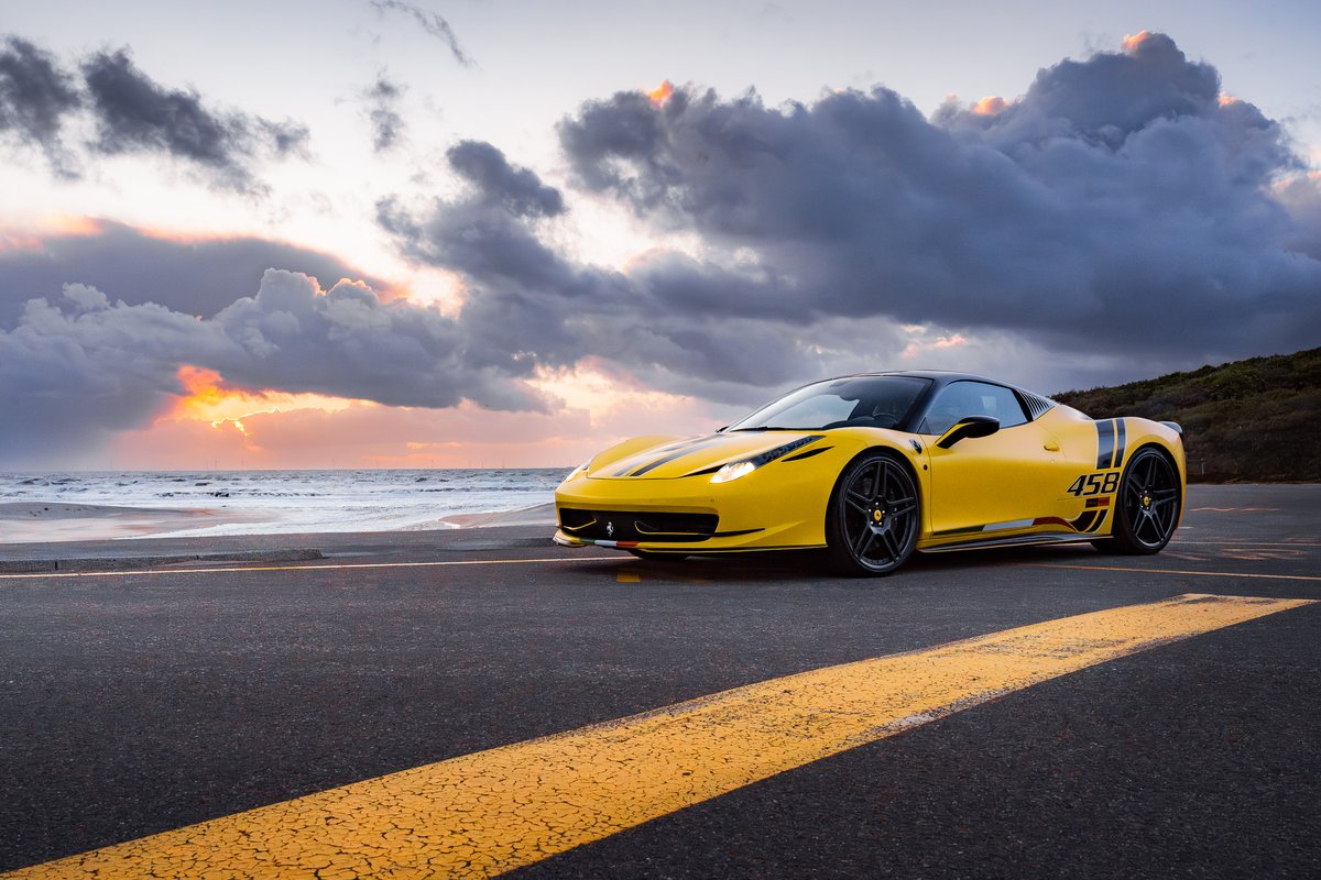Gele Ferrari 458 Speciale op de kustweg bij zonsondergang, commercieel campagnebeeld