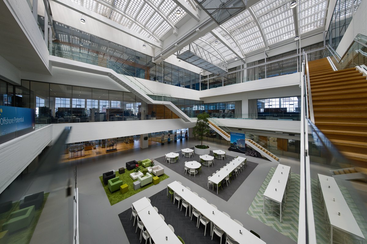 Interieurfoto van een modern kantooratrium met glazen daklicht en houten trap